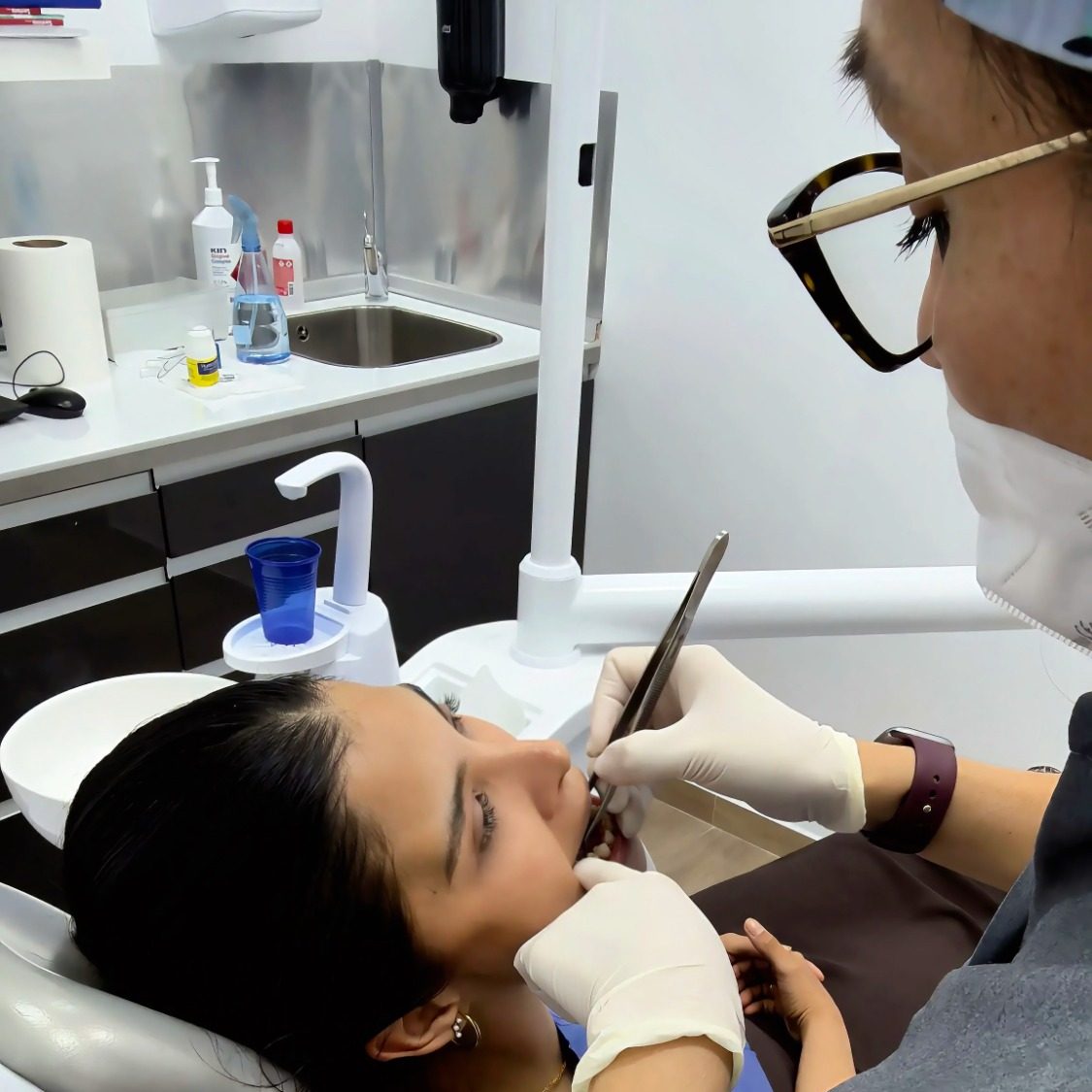 Dentista realizando un procedimiento dental a una paciente en un consultorio.