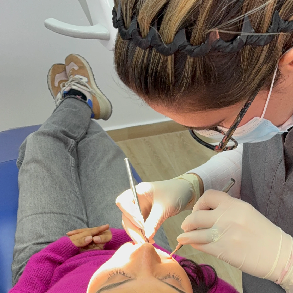 Dentista realizando un procedimiento dental a una paciente en un consultorio.