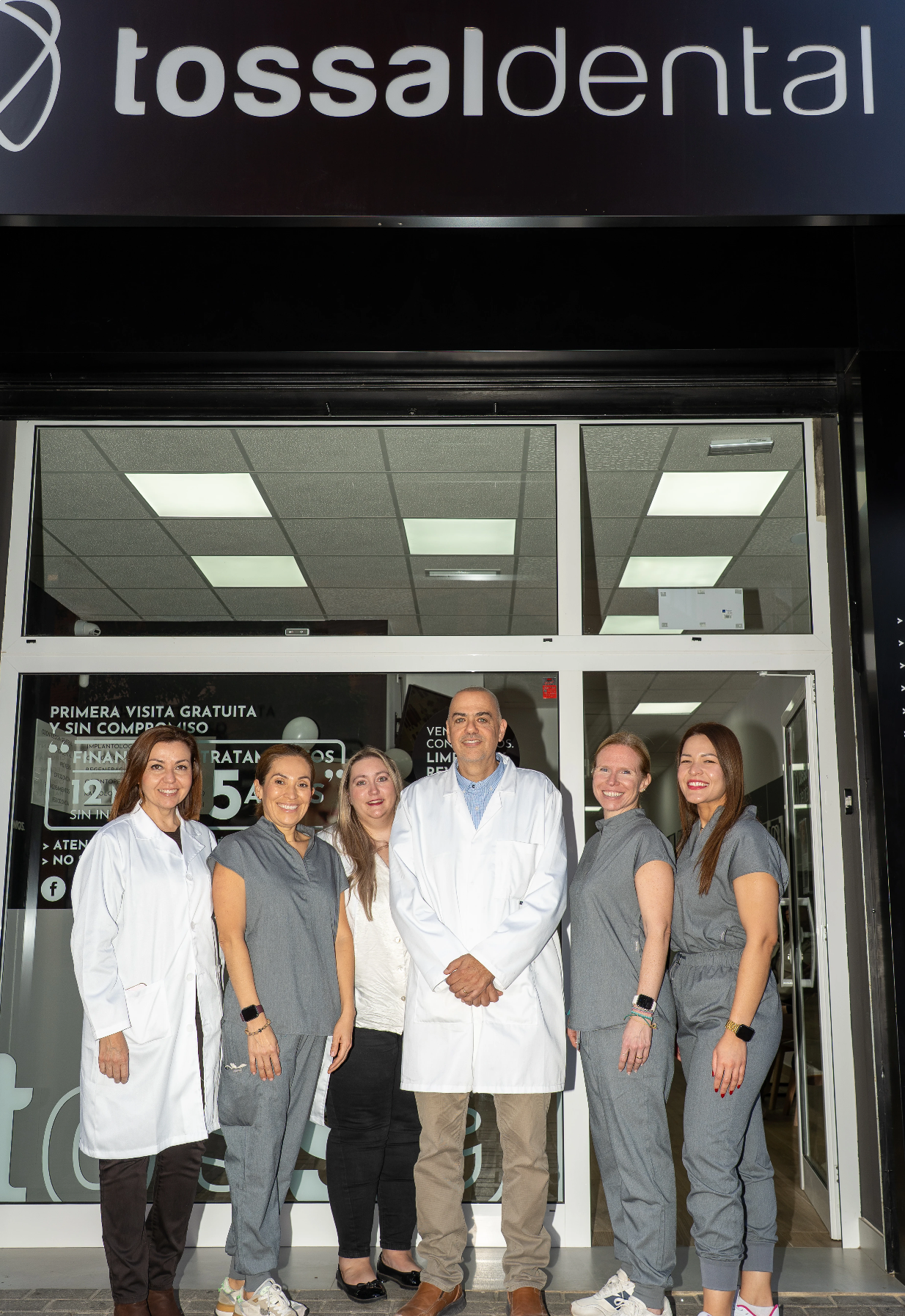 Grupo de profesionales sonrientes frente a la clínica dental Tossal Dental.