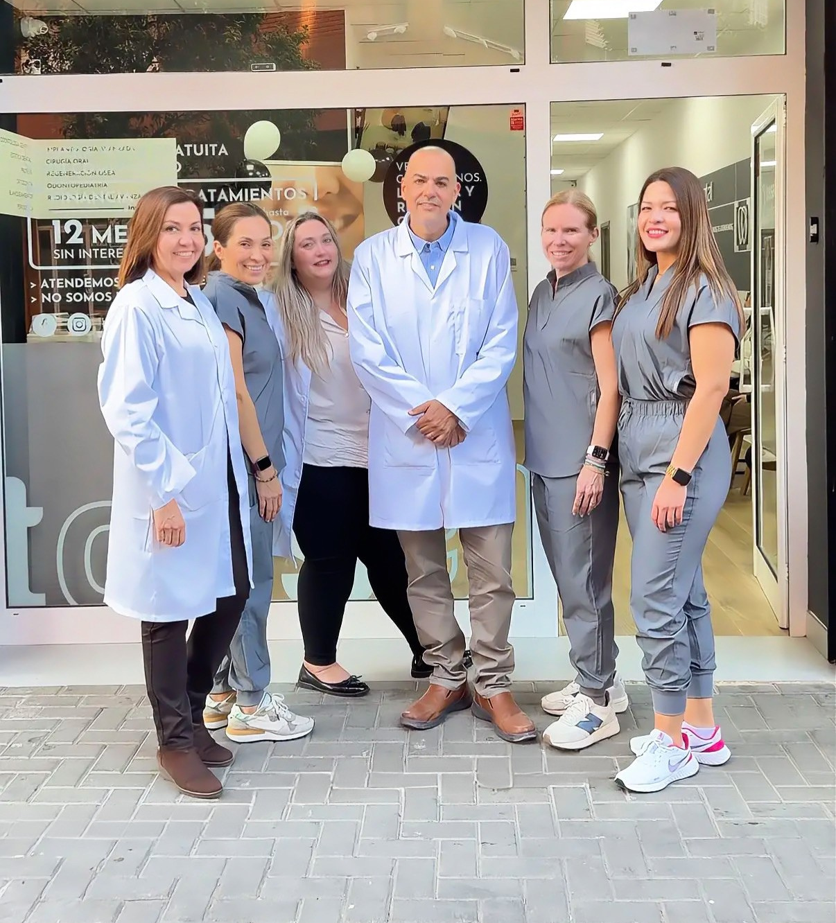 Grupo de profesionales sonrientes frente a la clínica dental Tossal Dental.